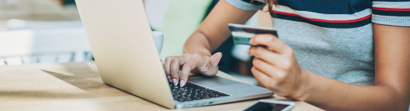 A woman using a debit card at a laptop computer