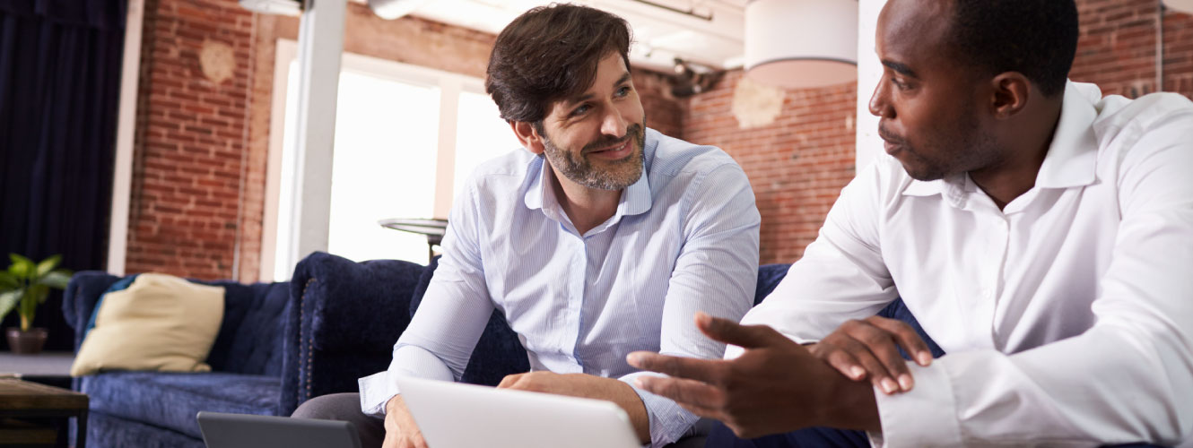 Business men talking while sitting on a couch.